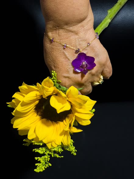 Primer plano del dije: una orquídea entera —pétalos, tallo y centro— suspendida dentro de la resina transparente