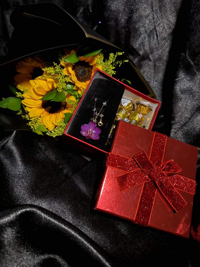 Una mujer con collar y anillo de orquídea preservada, de pie entre orquídeas vivas